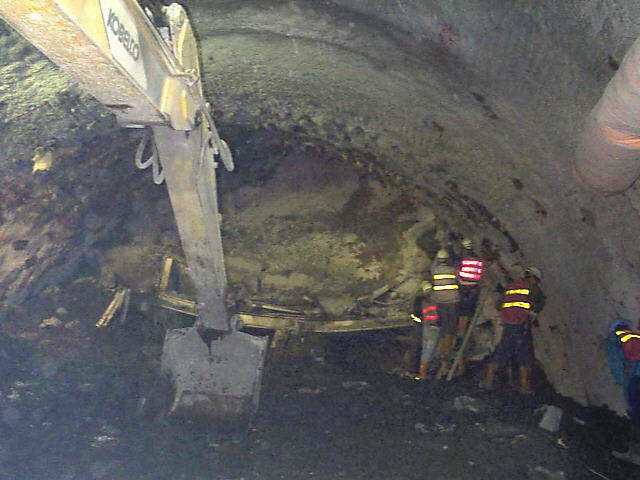 1998年雪隧抽坍，工程人員以機械手臂及人工小心清理崩落石塊。 本報資料照片