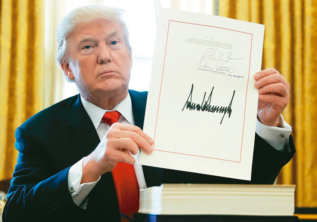 美國總統川普秀出簽署好的美國稅改法案。 路透社