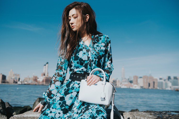 Selina穿湖藍色印花長裙9,700元、Nolita白色提包16,200元。圖／MICHAEL KORS提供