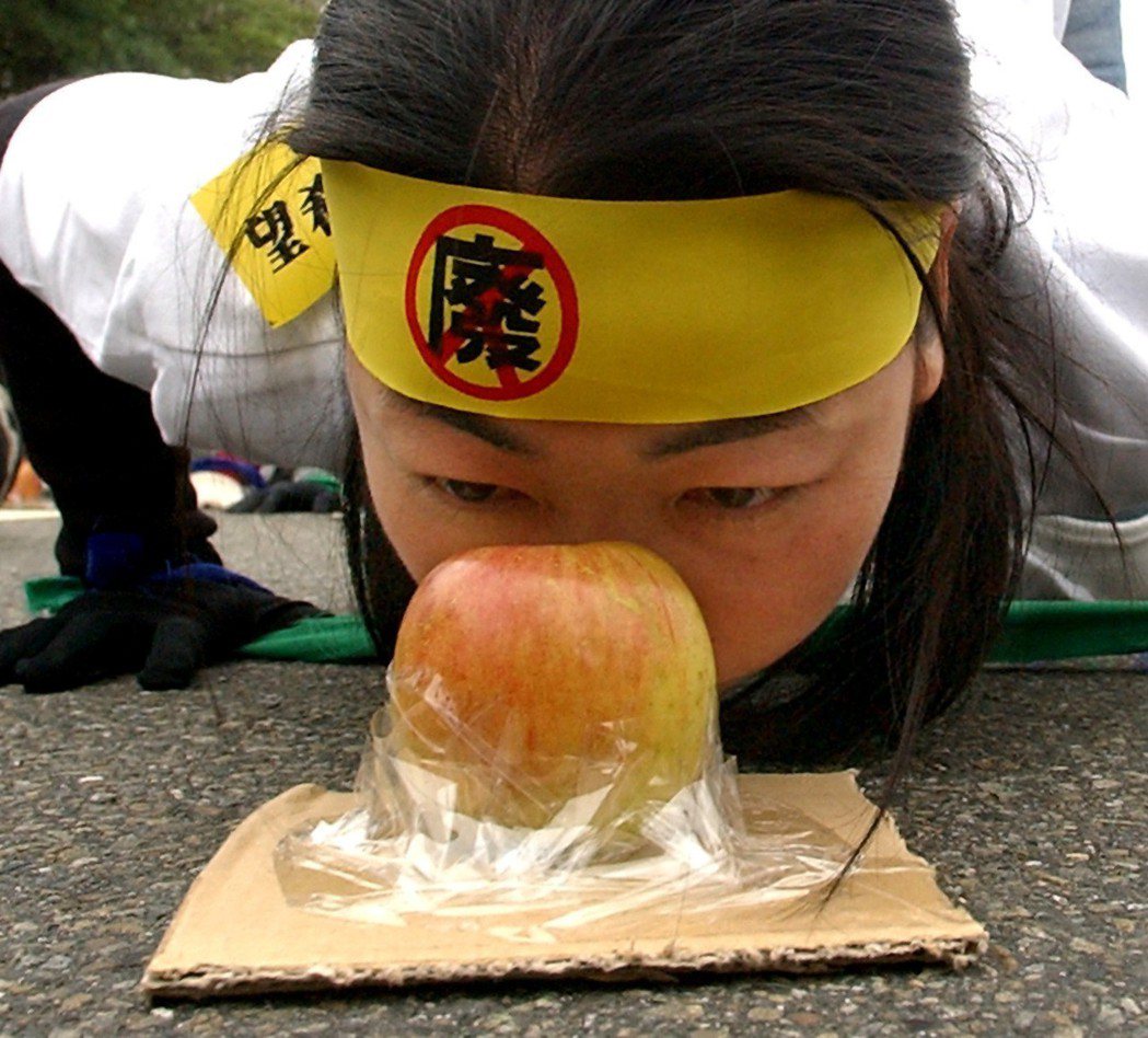 工人春鬥「拒吃爛蘋果，投出新希望」遊行，民眾身體低伏在地，用鼻子將象徵「爛蘋果」...