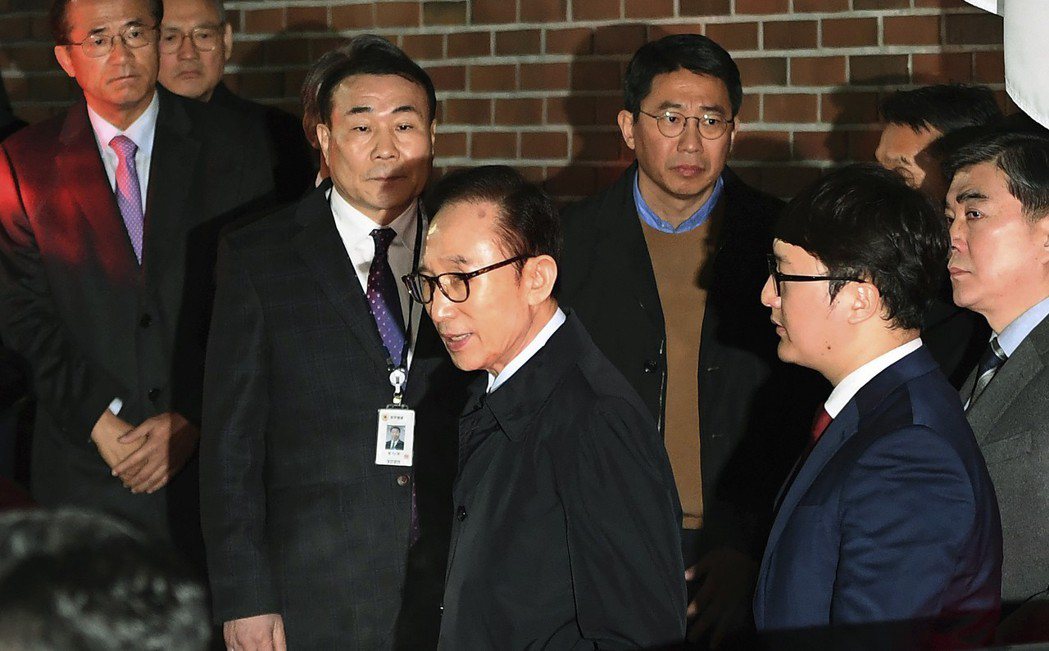 南韓前總統李明博於23日凌晨被手持法院逮捕令的檢調人員從住處帶往拘留所，他被控賄...