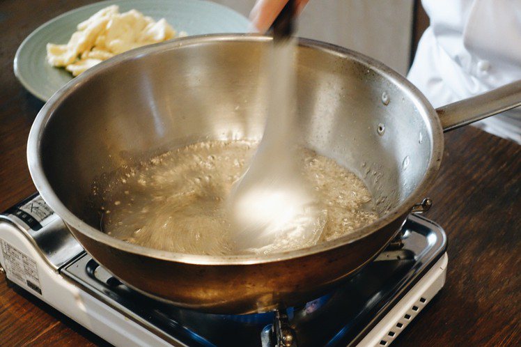 步驟3，準備另一個鍋子放少許溫開水，加入綿糖後以小火加熱，不斷攪拌成甘蔗色即可，接著將(2)放入鍋中攪拌。圖／記者沈佩臻攝影