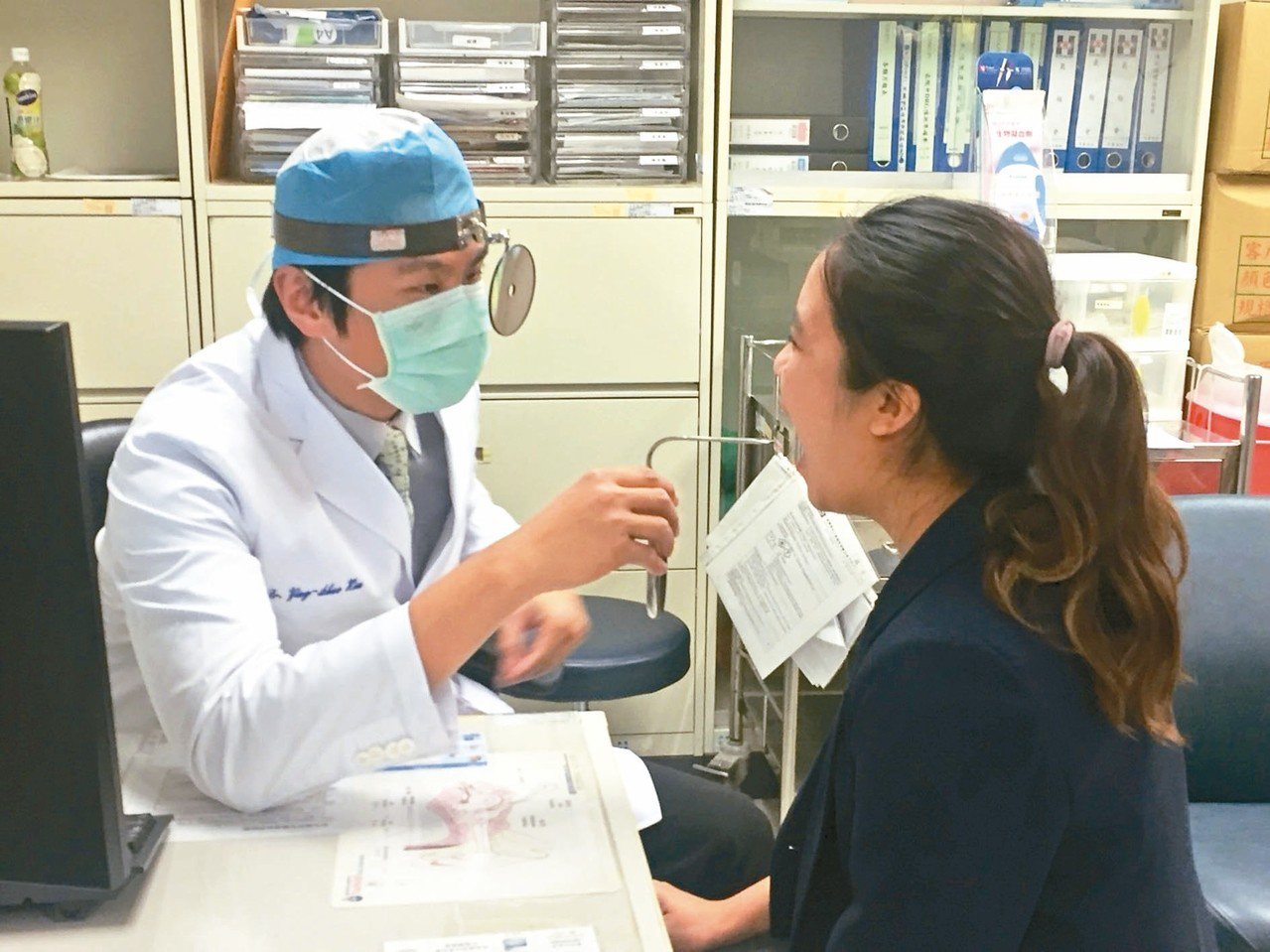 新光醫院耳鼻喉科醫師徐英碩(左)檢查病人喉部。
