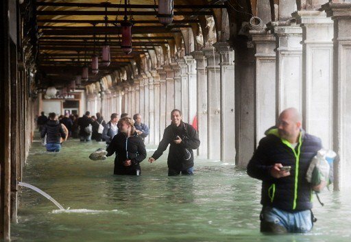 造訪威尼斯的遊客在水深及臀的積水中奮力前進。 （法新社）