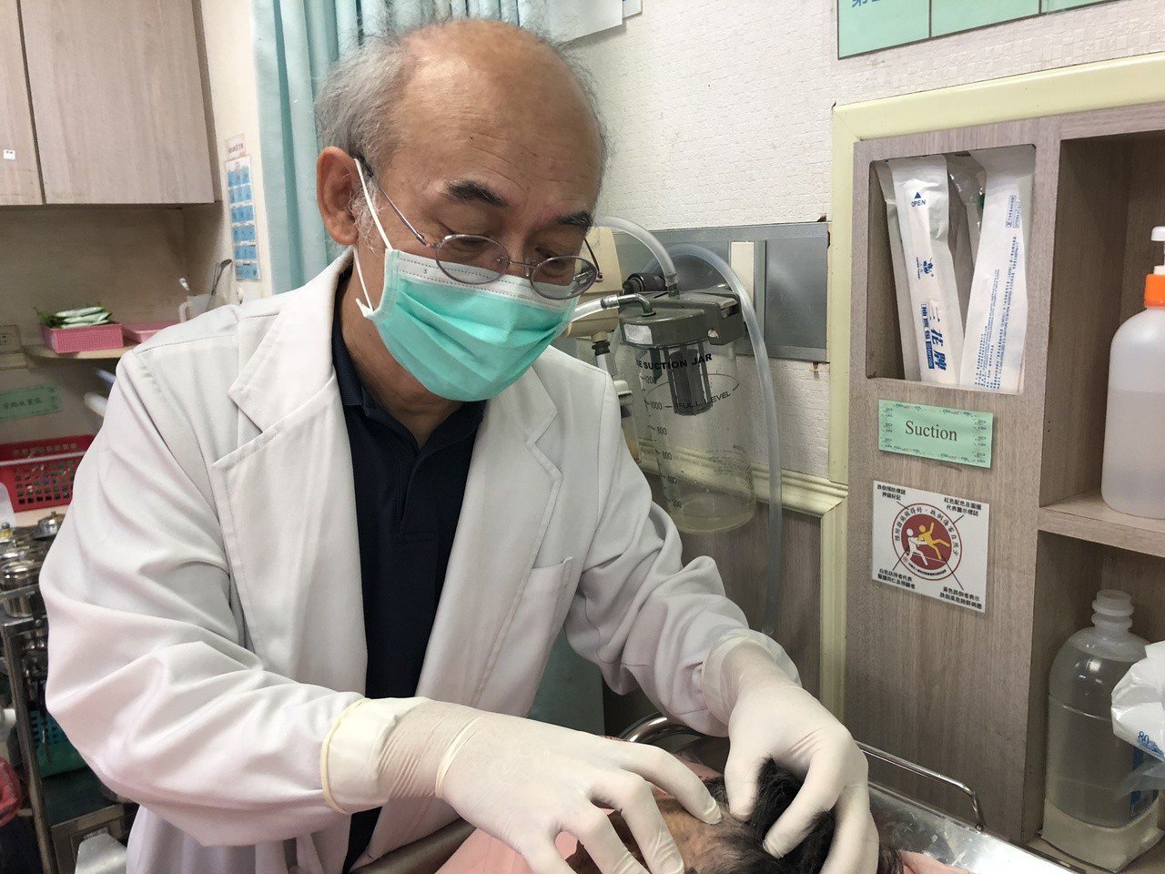 員林市宏仁醫院一般外科醫師梁鴻昌檢查病人的左額患部。圖／宏仁醫院提供