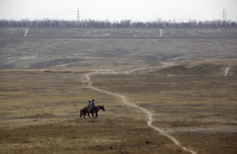 兩名男子在北京郊外永定河乾涸的河道上騎馬。路透
