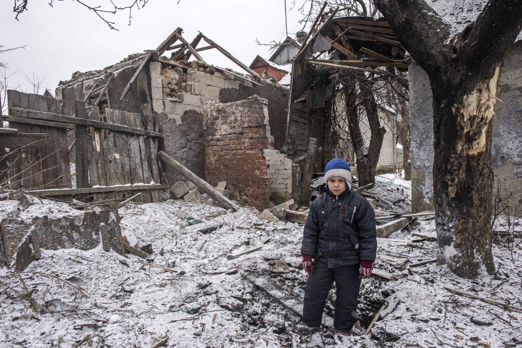 在接近前線的烏克蘭阿夫傑夫卡市，一個8歲男孩站在被砲彈炸毀的家門口。 （美聯社）