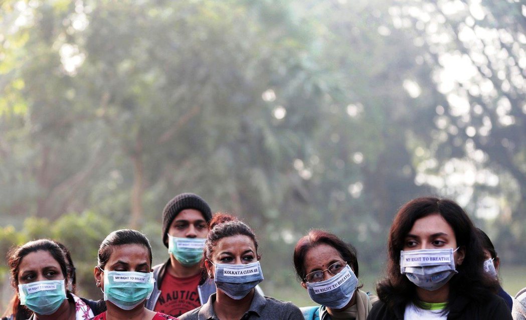印度空汙嚴重，加爾各答民眾戴有標語的口罩上街抗議。圖／歐新社