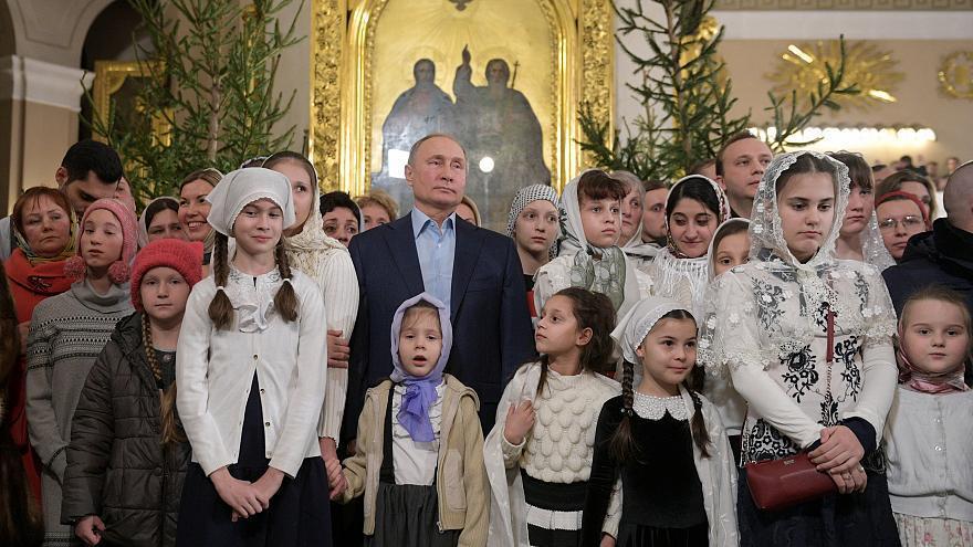 普亭（中）日前在聖彼得堡東正教教堂內跟民眾慶祝耶誕節。 （路透）