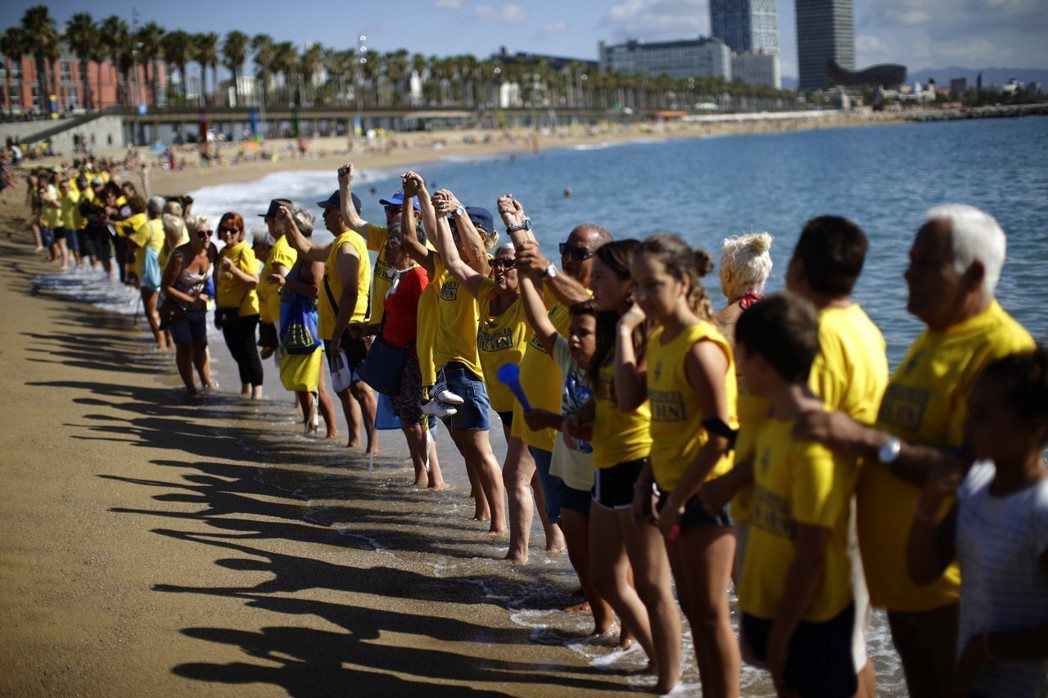 巴塞隆納居民沿著沙灘排成長隊伍，抗議遊客過多。 （美聯社）