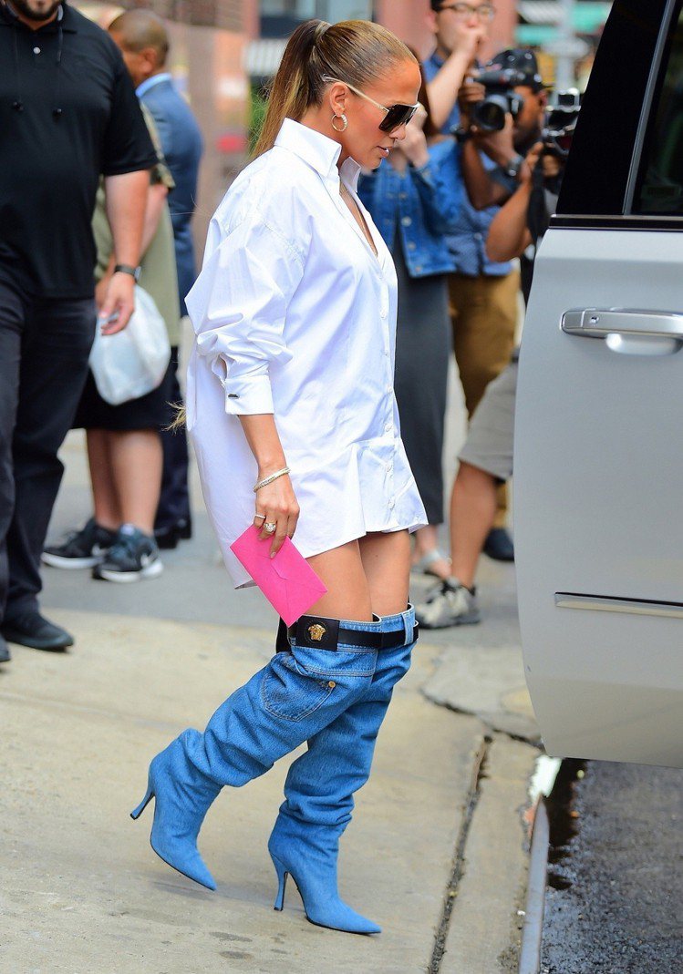 珍妮佛洛佩茲穿白色Oversize襯衫上街，搭配Versace早春的牛仔高跟長靴。圖／Versace提供