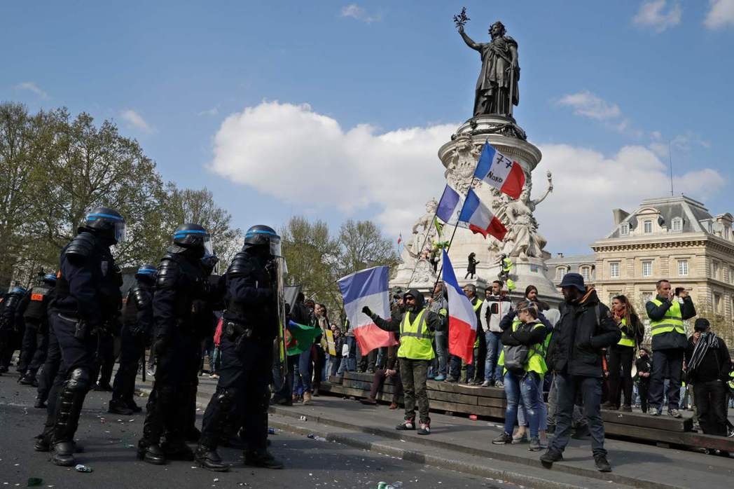 示威民眾13日穿著黃背心在巴黎街頭抗議，這是黃背心運動連續第22個周末舉行。（法...