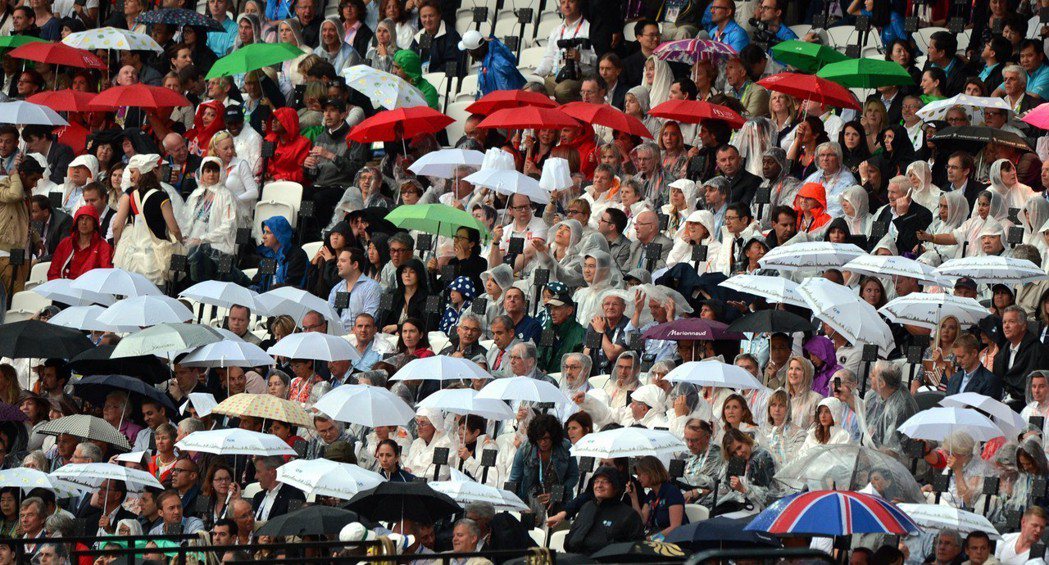 2012倫敦奧運在雨中迎開幕，觀眾在開幕式前撐傘觀看表演。 新華社