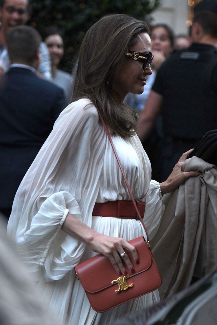 安潔莉娜裘莉身穿THE ROW縐褶長袍，配襯CELINE Triomphe手袋。圖／取自www.whowhatwear.com