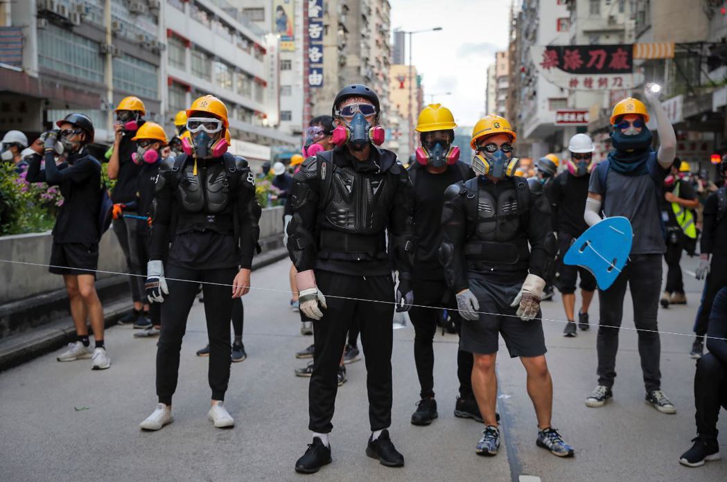 蒙面的黑衫戰士穿梭於夏日危城的街道，線上遊戲般的游擊戰，在香港實境上演。 圖／美聯社