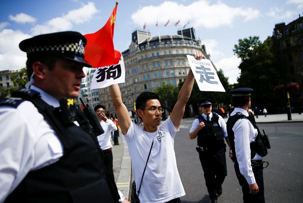 本月17日在倫敦市中心，一名「撐中國」的中國示威者手持五星旗與「走狗」標語，對聲援反送中的民眾嗆聲。 圖／路透社