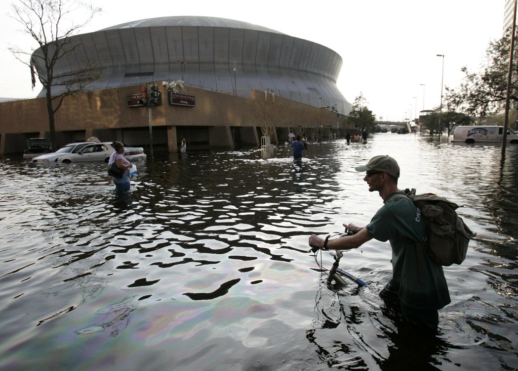 2005年卡崔娜颶風侵襲美國奧爾良，造成洪水氾濫，一名男子推著腳踏車涉水經過。 ...