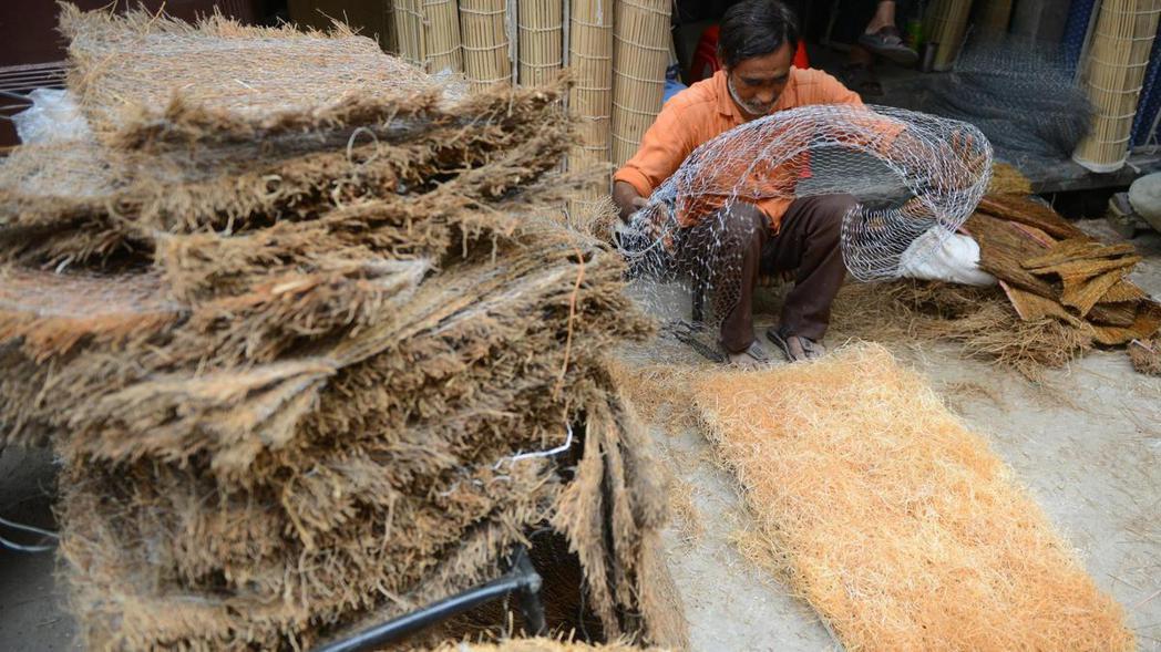 一名印度工人正在編織草蓆，為製作「稻草冷氣」作準備。 圖／The Nationa...