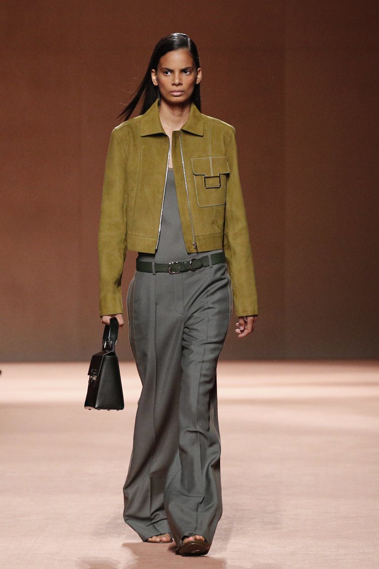 Hermès的苔綠色皮革工裝夾克，搭配灰色低腰寬褲，中性的服裝線條，替女性帶來更多穿搭的可能。圖／美聯社