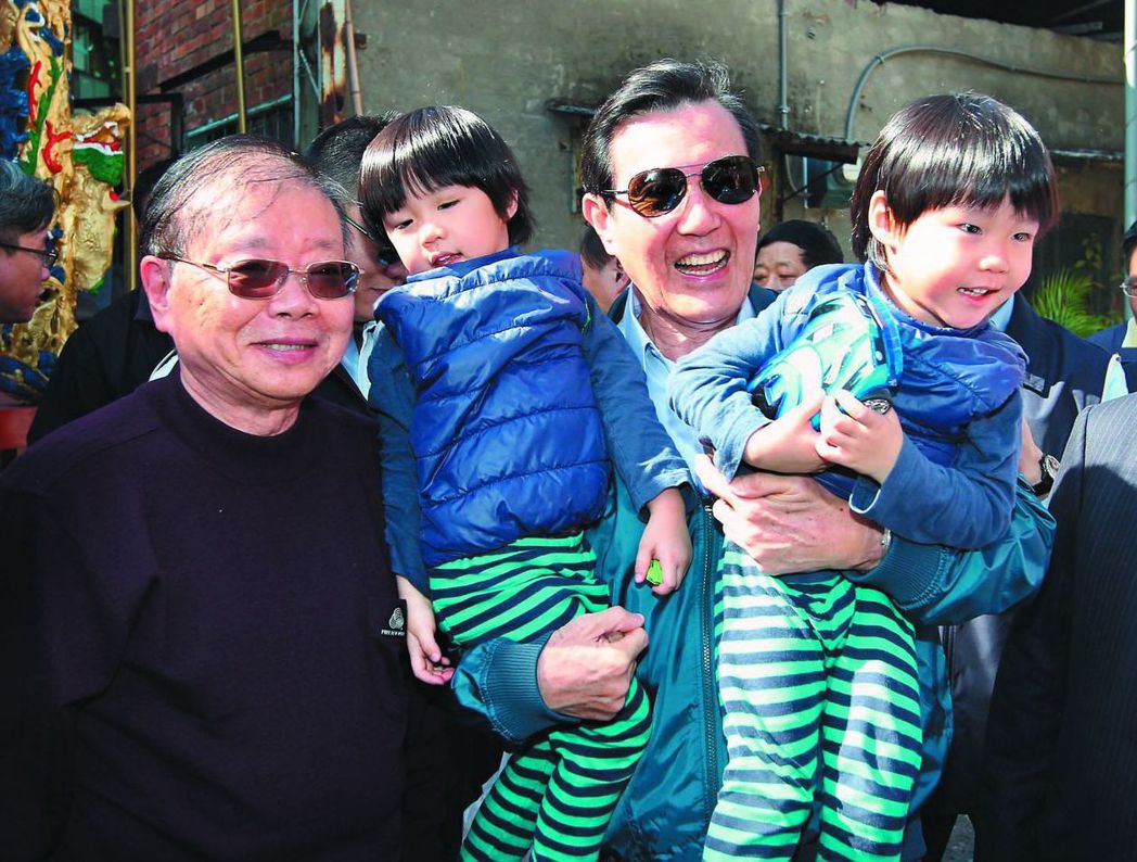 前年春節，馬英九一手一個抱起雙胞胎小朋友拍照。 （中央社）