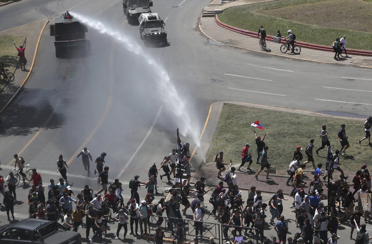 智利警察22日在聖地牙哥以水車試圖驅散示威者。（美聯社）