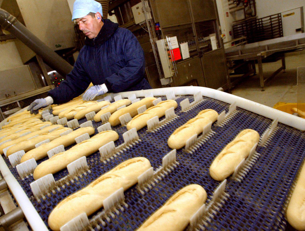 法國蘭斯市一名麵包師正在檢查剛做好的長棍麵包。 （法新社）
