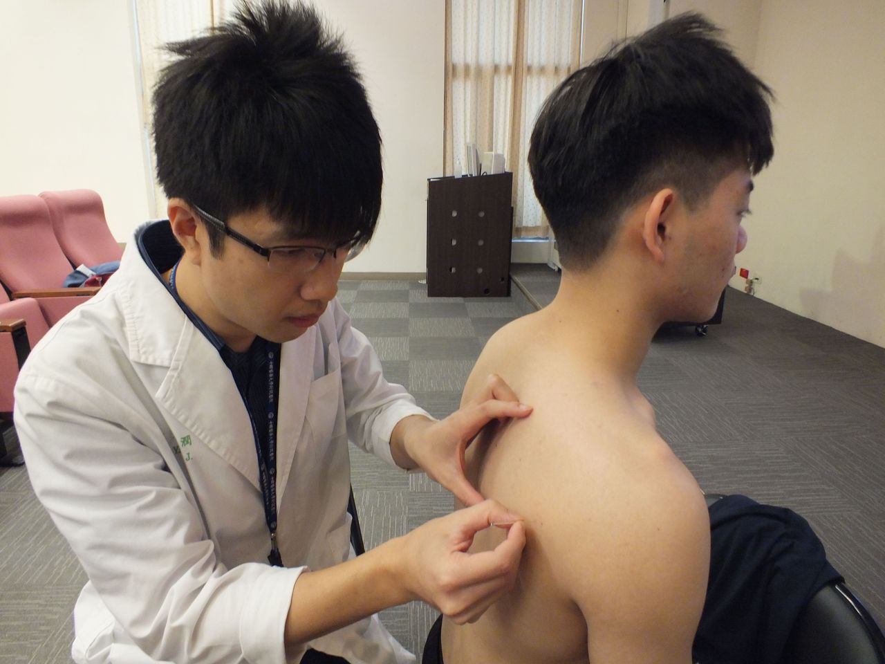 醫師楊潤（左）說明，陳姓大學生（右）勤練重訓，透過針灸激痛點治療兼保養，讓運動生涯健康長久。記者趙容萱／攝影