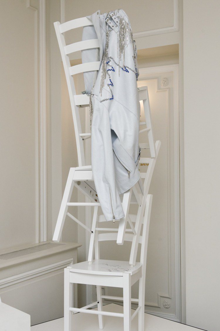 Jean-Claude Jitrois把白色的椅子堆疊成一座塔，上面掛了他最知名的設計—皮革外套。圖／摘自WWD