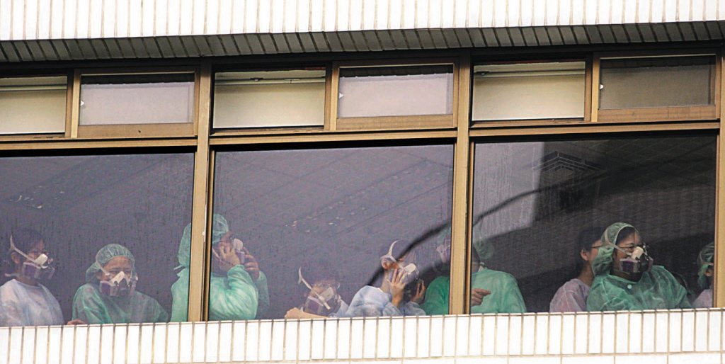 2003年4月27日，和平醫院遭隔離的第4天，一群醫護人員聚集窗邊，神情嚴肅。