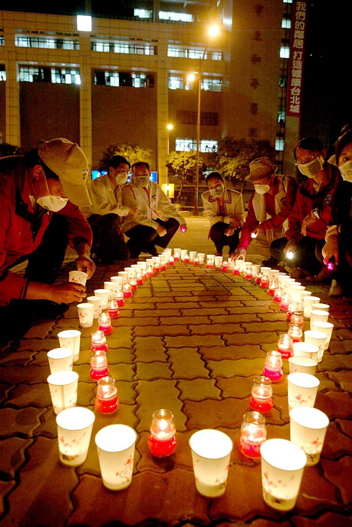 國際青商會員在和平醫院前點著圍繞成台灣形狀的蠟燭，為院內和SARS奮戰的醫護群及台灣島祈福。記者胡國威／攝影