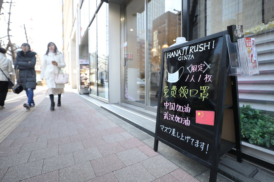 東京銀座的商鋪門前，招牌上寫著免費贈送口罩和為武漢加油鼓勵的內容。 （中新社）