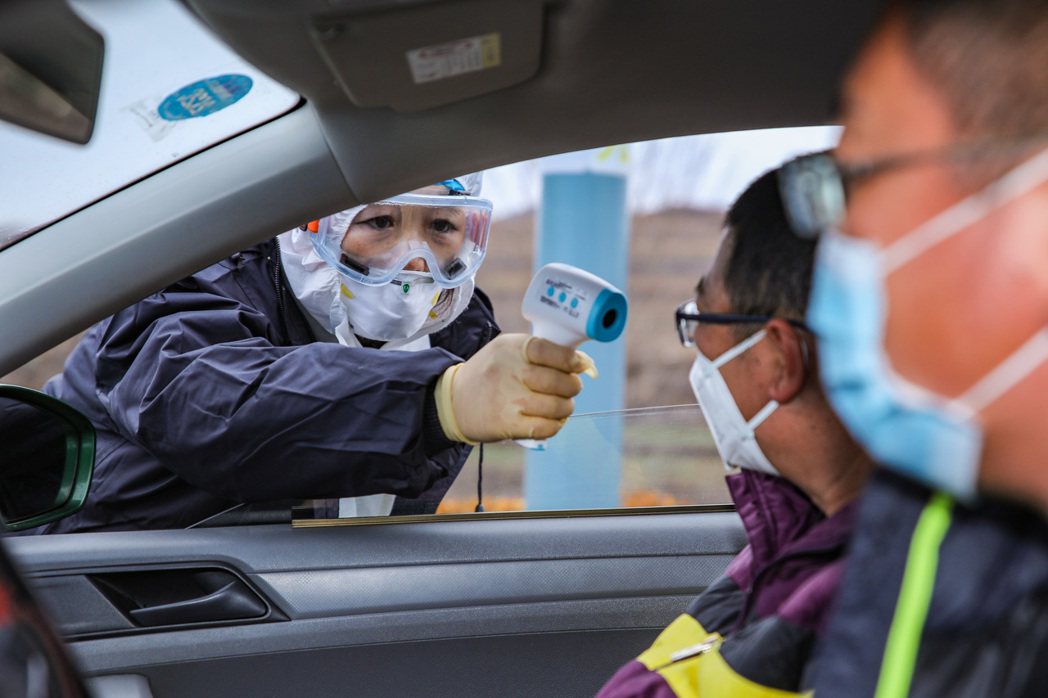 山東榮成疾控中心人員對進城車輛的駕駛人員及乘客，檢測體溫。 （新華社）