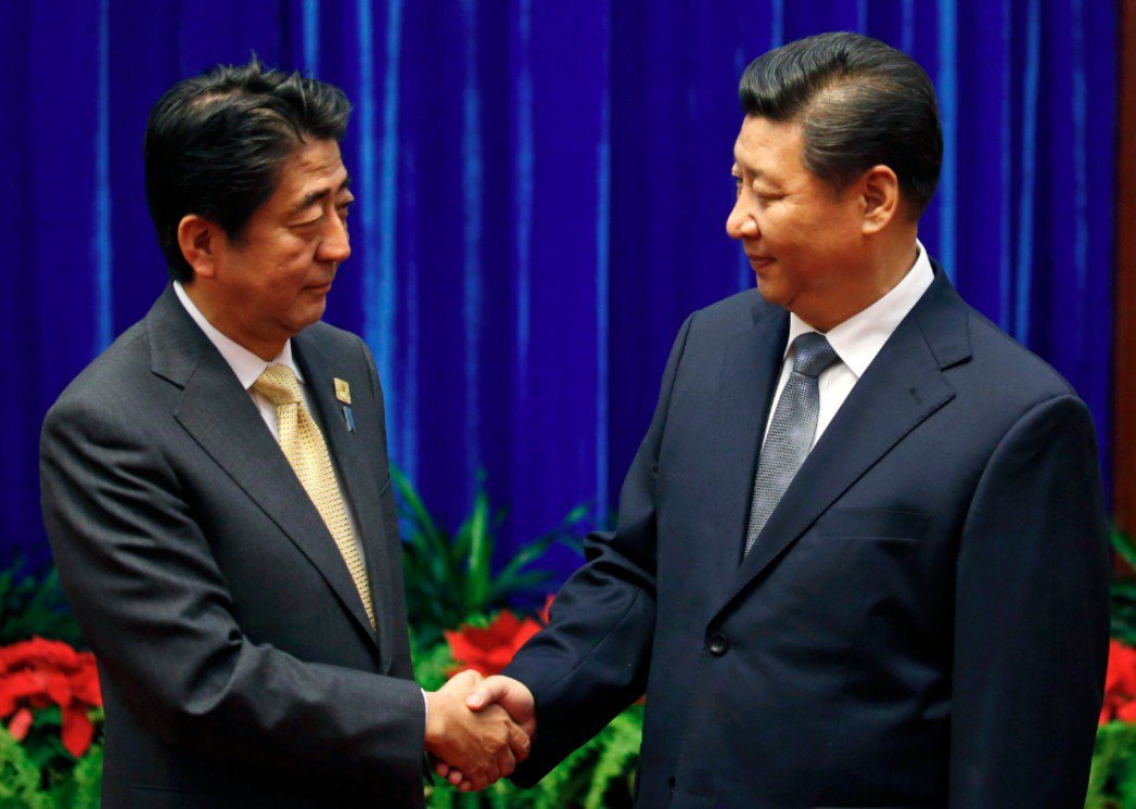 安倍（左）跟習近平在2014年APEC上握手。（路透）