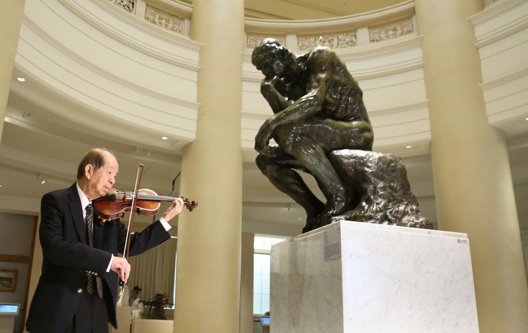 奇美集團創辦人許文龍在奇美博物館羅丹廳拉小提琴，與羅丹的作品「沉思者」對話。 聯...