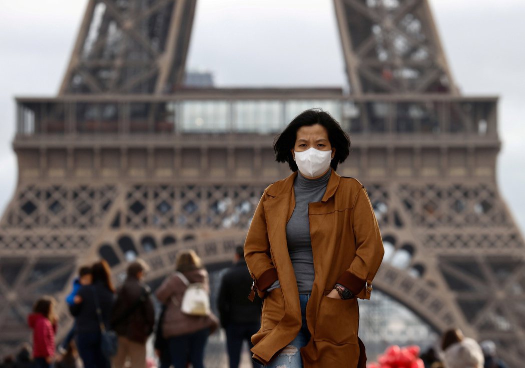 在歐洲，針對亞裔人士的種族歧視事件時有所聞。圖為一亞裔女子戴著口罩行經艾菲爾鐵塔...