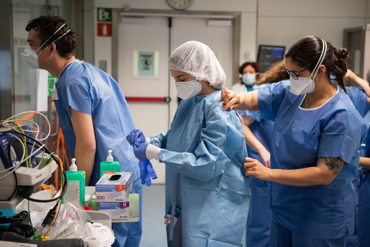 圖為西班牙巴塞隆納一間醫院的醫護人員正在穿防護衣。新華社