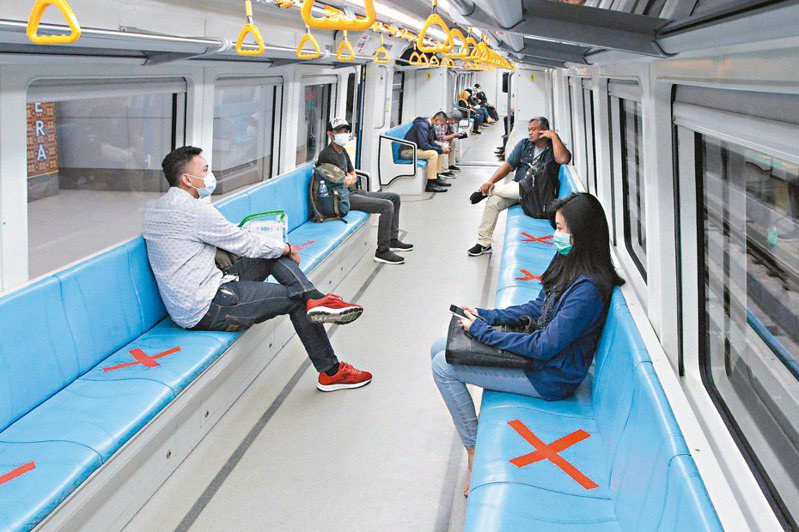 印尼蘇門達臘南部巨港民眾廿日搭乘輕軌列車時，避免坐在紅色叉叉標記的座位，保持社交距離防疫。 （法新社）