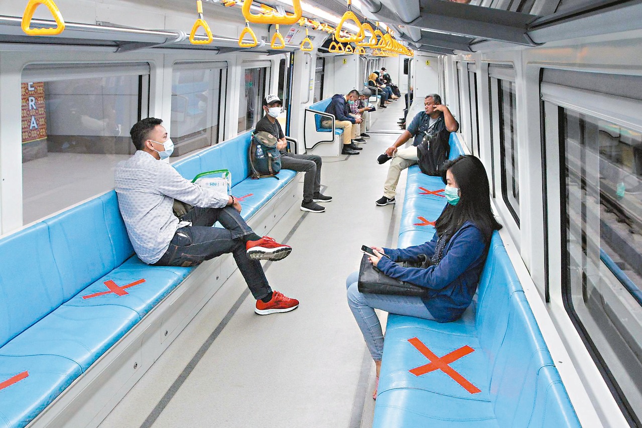 印尼蘇門達臘南部巨港民眾廿日搭乘輕軌列車時，避免坐在紅色叉叉標記的座位，保持社交距離防疫。