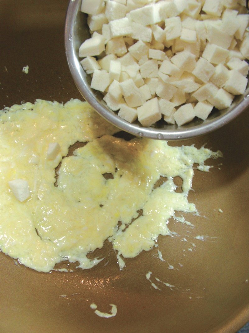 將雞蛋放入炒至半熟。 然後將饅頭丁放入炒散，煎至香脆。 圖／幸福文化提供