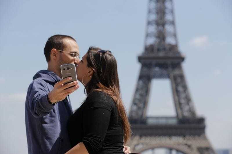 一對情侶在巴黎鐵塔前自拍，留下甜蜜的造訪紀錄。 圖／路透社