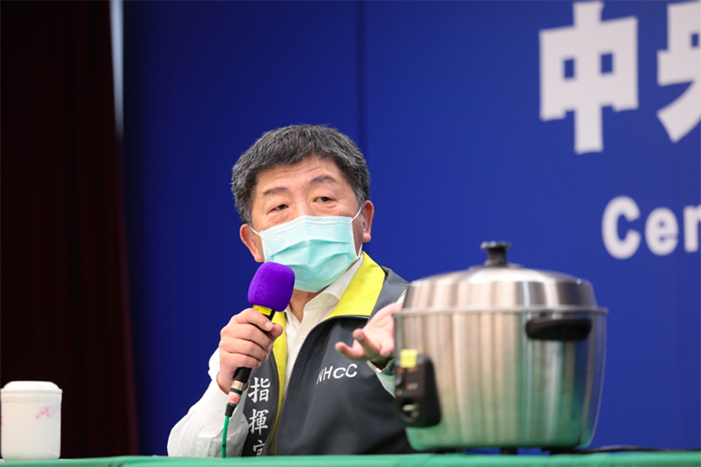 中央流行疫情指揮中心指揮官陳時中於4月5日記者會上，示範電鍋乾蒸口罩的流程。 圖／流行疫情指揮中心提供