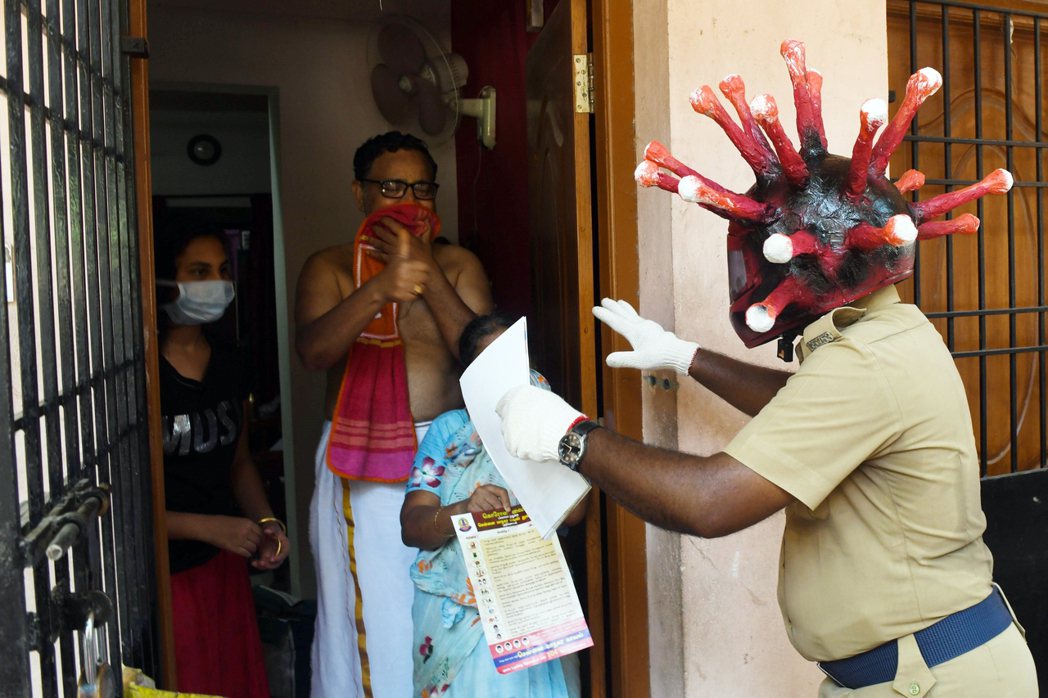 圖為印度警察向民眾傳發防疫相關宣導，並特地頭戴「病毒」安全帽，以警示民眾。 圖／...