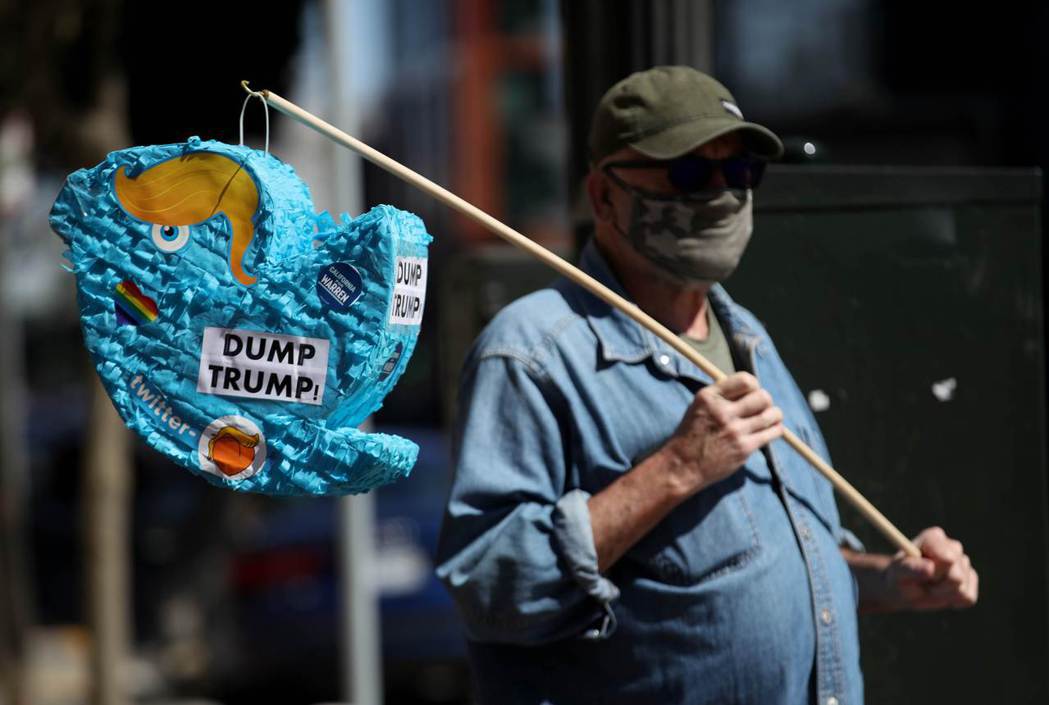 圖為28日，一名美國民眾拿著Twitter標誌物，上面寫著「垃圾川普」（DUMP...
