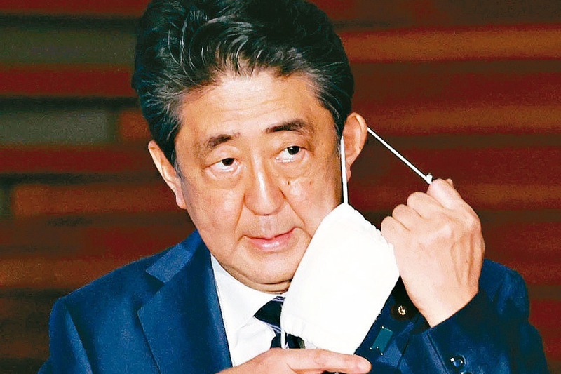 日本政府將在25日全面解除境內「緊急事態宣言」，日本首相安倍晉三21日在官邸脫下小一號的口罩。 路透