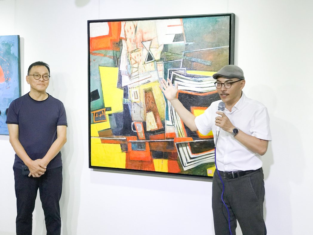 策展人洪明爵（右）說林熺俊的畫作「再創世界的新空間美學」。 攝影／張世雅