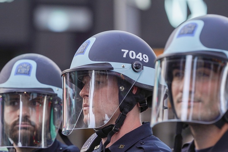 三名沒戴口罩的紐約市警察5月30日在時報廣場看著抗議者。歐新社