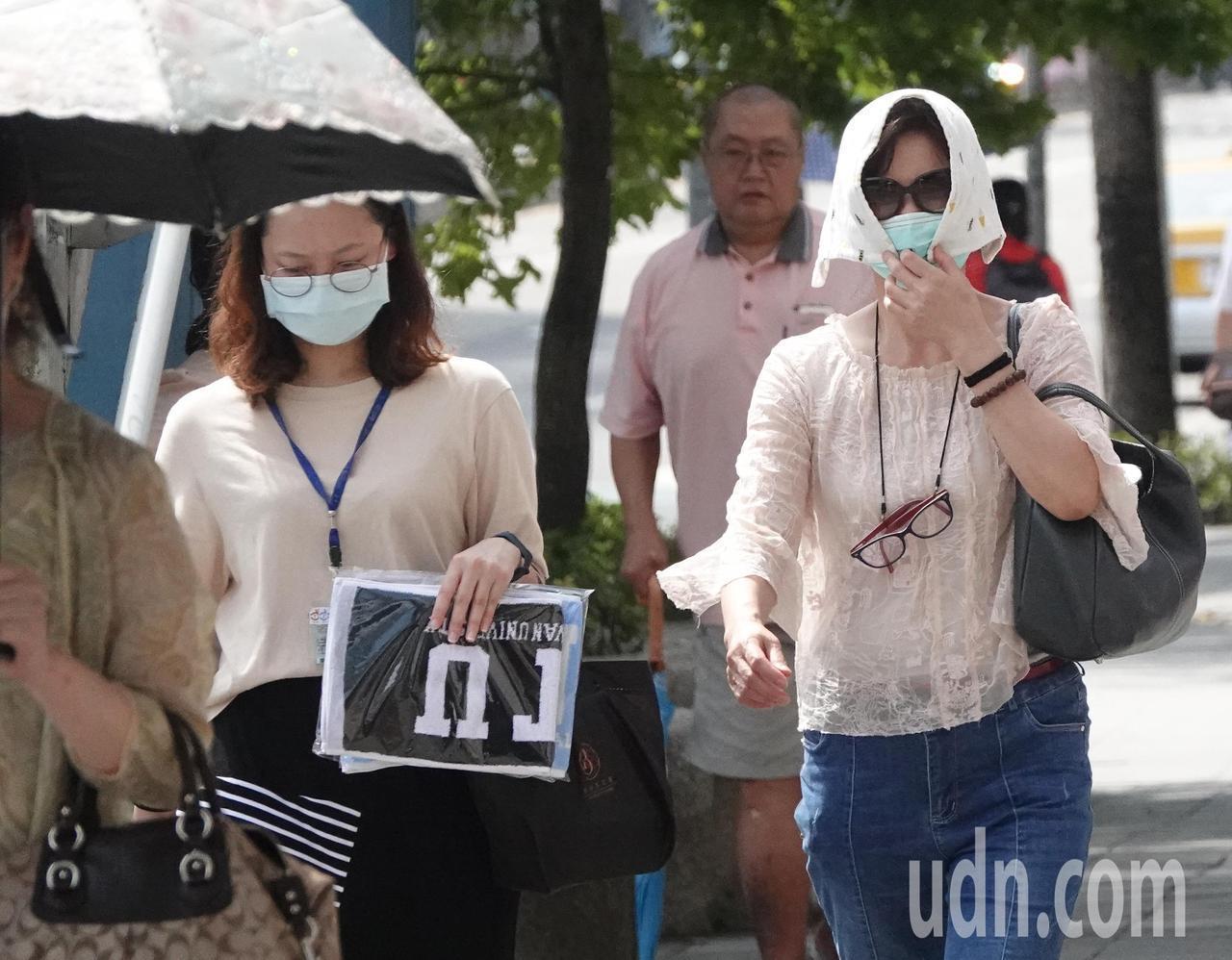 台北街頭飆高溫，有民眾用毛巾蓋頭防曬。報系資料照片