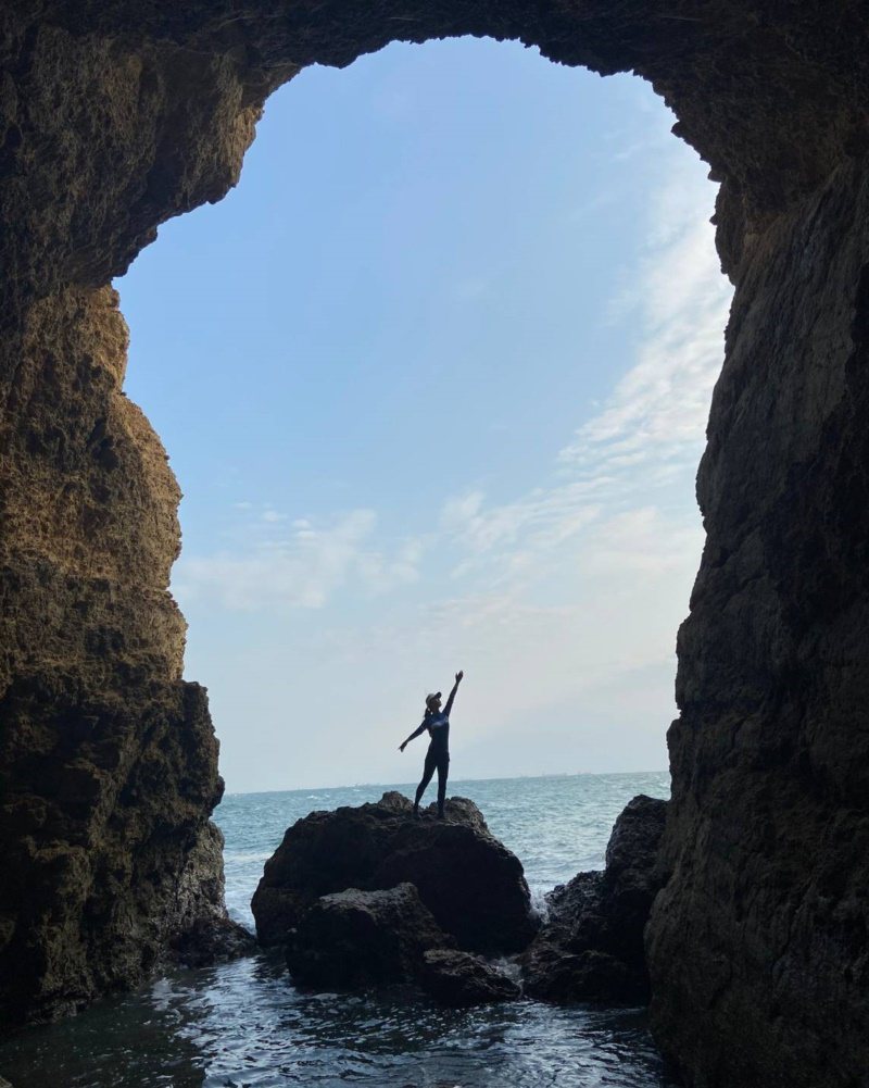 遊客站在高雄柴山大自然海蝕洞上拍照，畫面相當夢幻。 圖／讀者提供