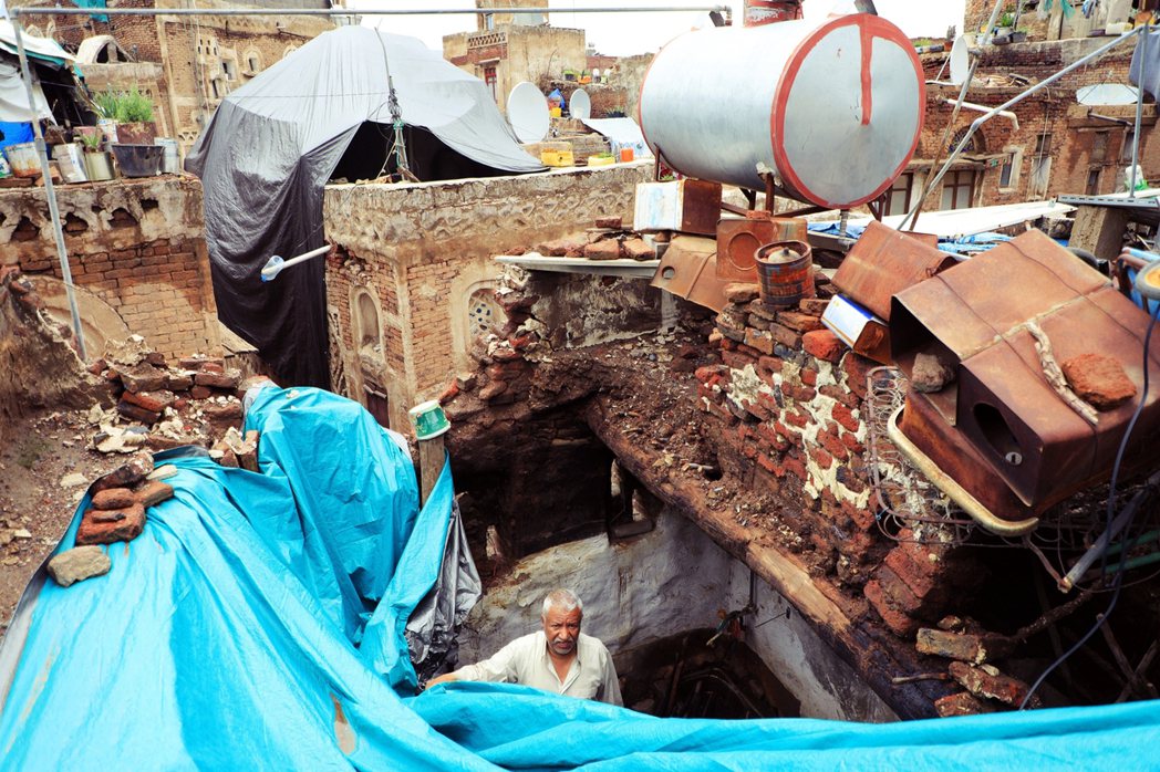 沙那舊城區災民，自家屋頂坍塌後，只能用塑膠布料臨時遮蓋。 圖／法新社