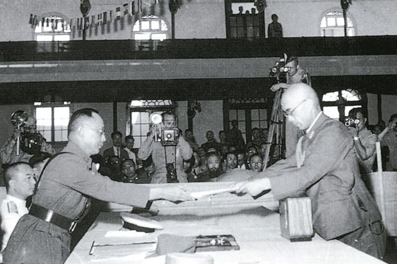1945年9月9日的南京受降典禮，日本駐華派遣軍總司令岡村寧次簽署降書後，由參謀長小林淺三郎（右）呈遞給何應欽（左）。 圖／國防部提供